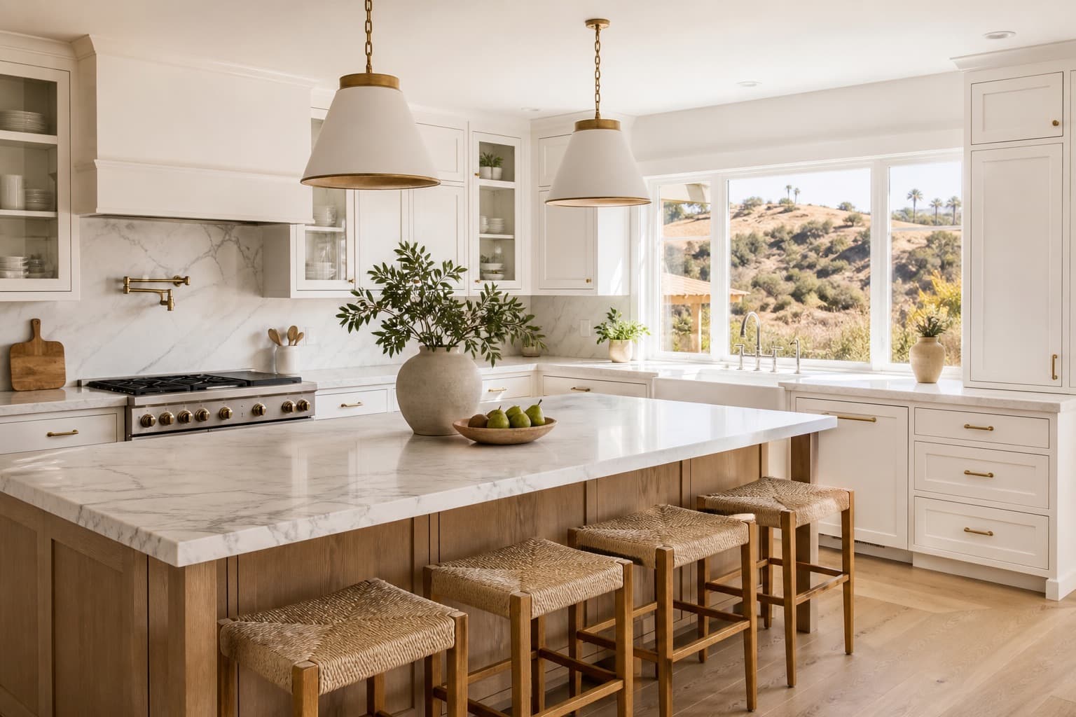 A bright kitchen with a marble island and hillside views through the windows