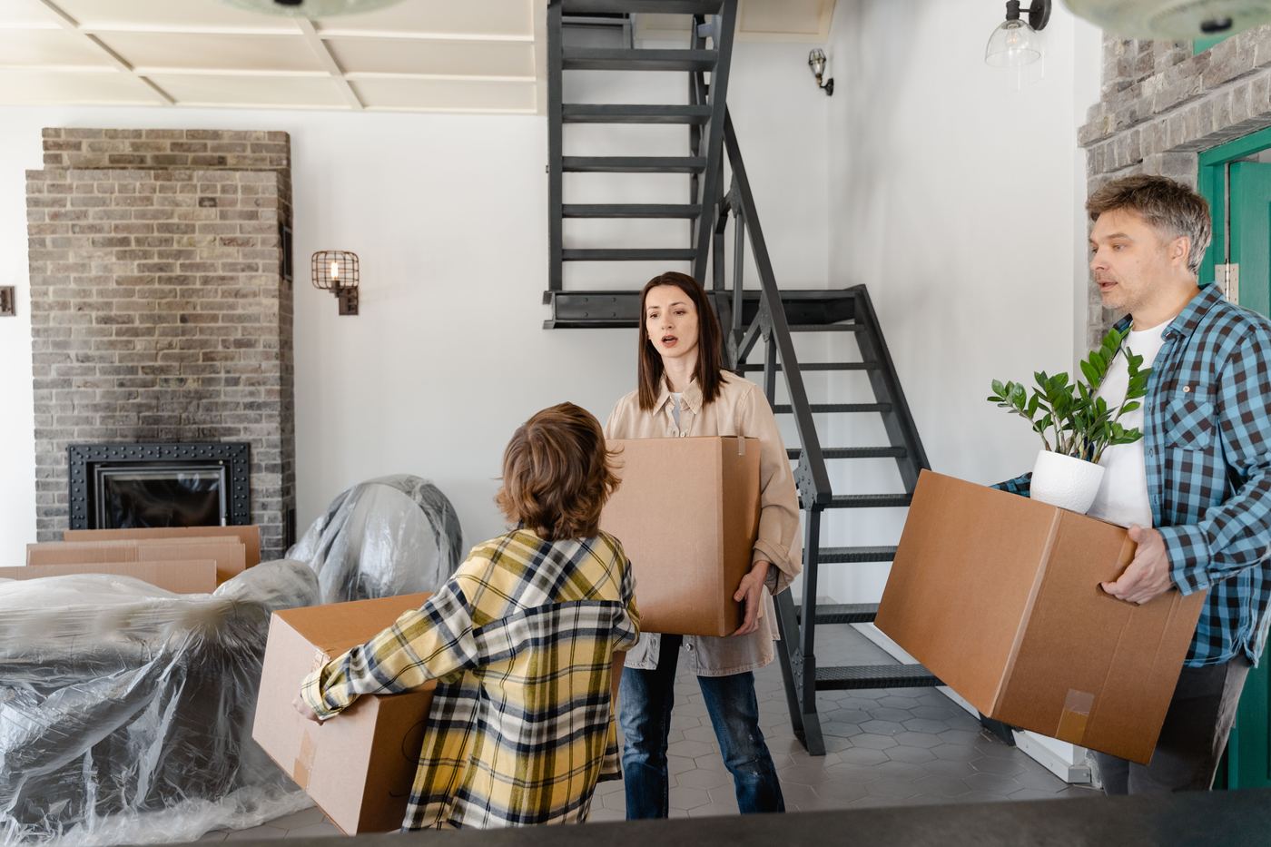 Family carrying moving boxes into a new home, considering a move from Los Angeles to Newhall in Santa Clarita