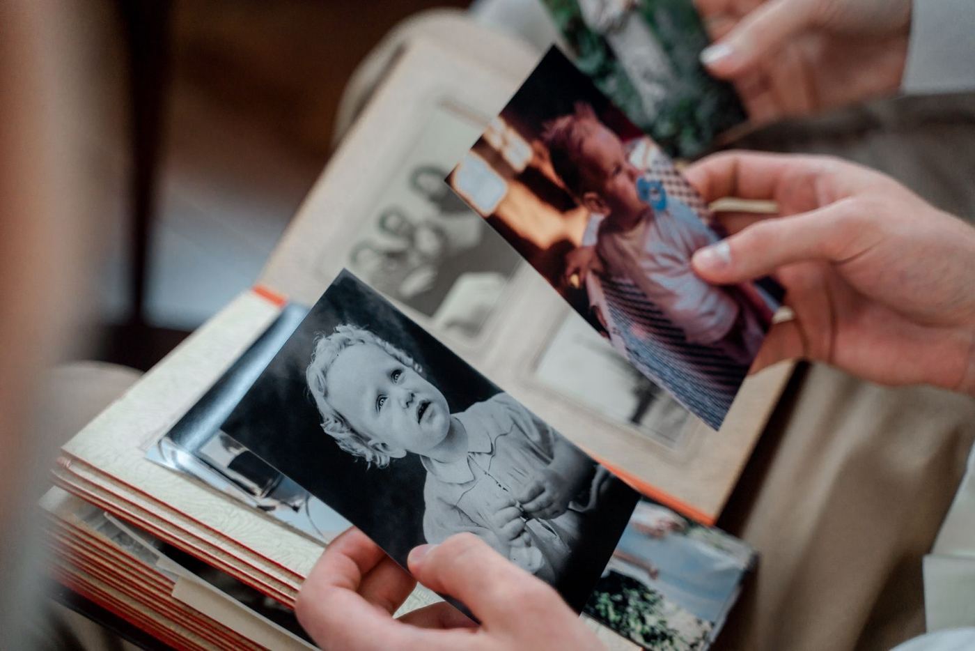 Close-up of hands sorting through an old family photo album, representing an inherited home in Stevenson Ranch