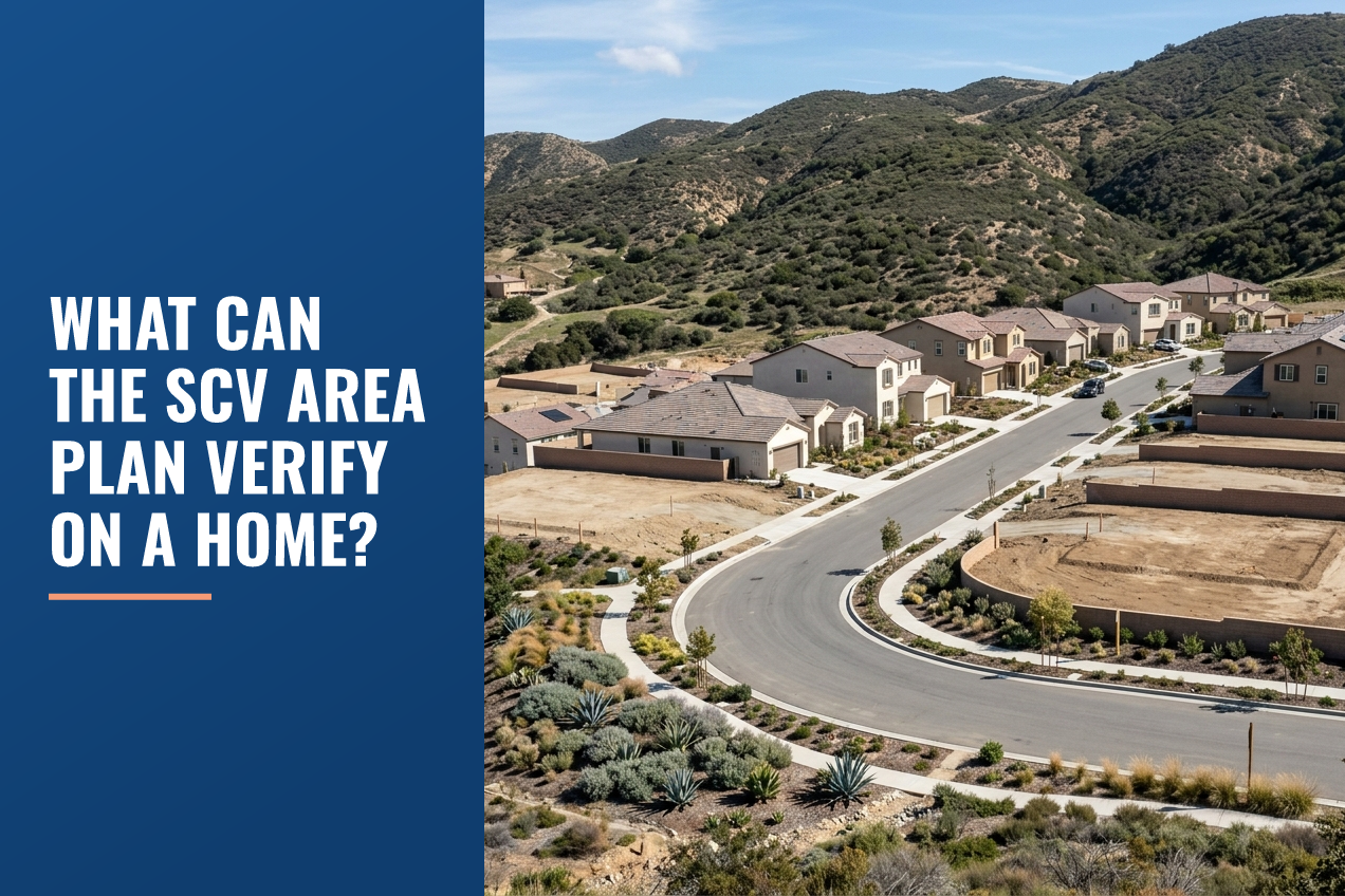 Aerial view of a suburban neighborhood in the Santa Clarita Valley with residential houses, vacant lots, and foothills under a clear sky.